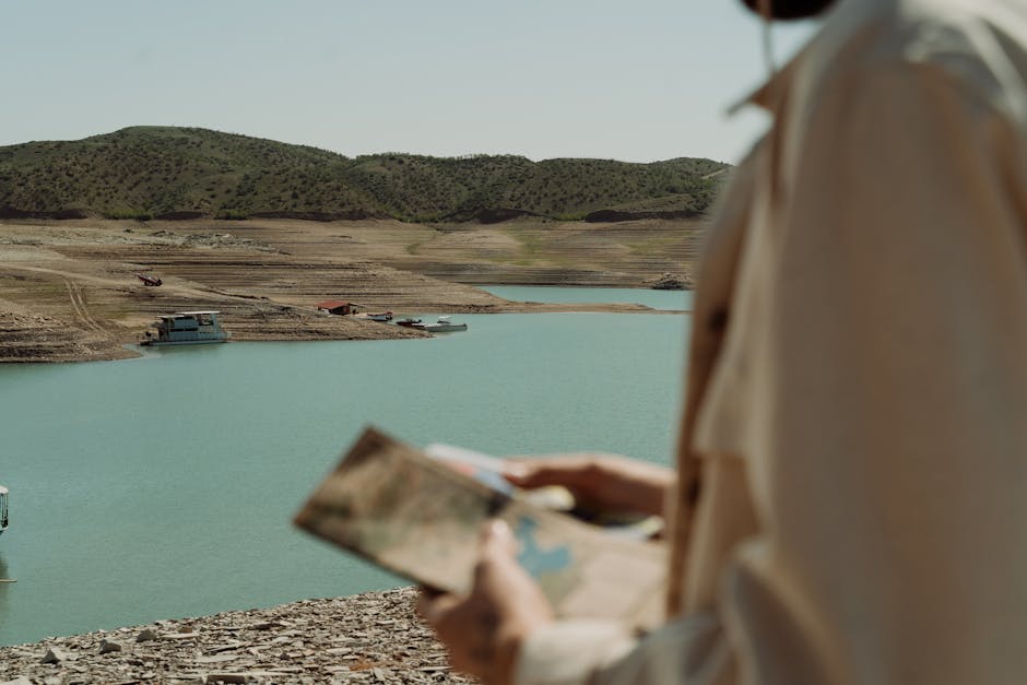Traveler studies map by tranquil lake surrounded by hills.