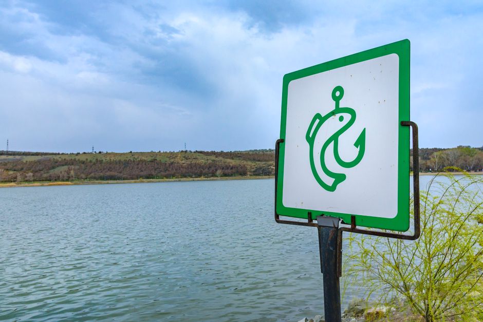 A fishing sign with a lake and blue sky backdrop, symbolizing outdoor recreation and nature.